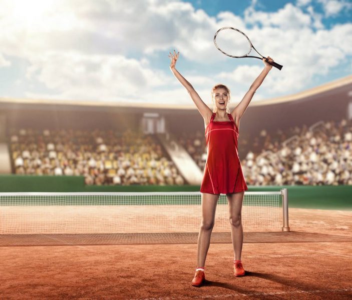 female tennis player on a tennis court holding a tennis racket above her head and celebrating a victory